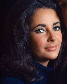 a close up of a woman with long hair and blue eyes posing for a photo