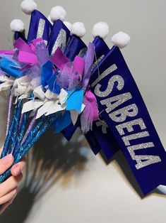 a person holding up a purple and blue bouquet with pom - poms on it