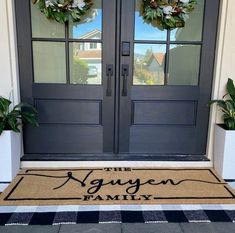 two wreaths on the front door of a house with an agingen family mat