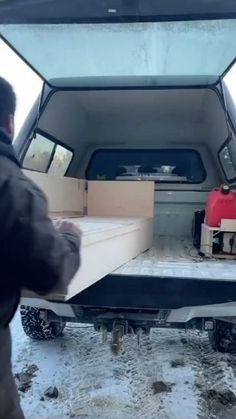 a man unloading boxes from the back of a pickup truck in the wintertime