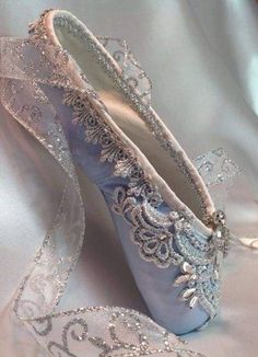 a pair of blue ballet shoes sitting on top of a white satin fabric covered floor