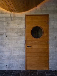 a wooden door in front of a white wall with a circular mirror on it's side