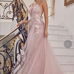 a beautiful woman in a pink dress standing on the stairs with her hand on her hip