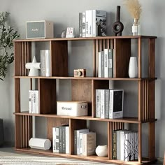 a bookshelf filled with lots of books next to a plant and vases