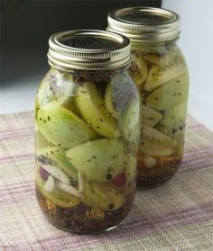 two jars filled with pickles sitting on top of a table