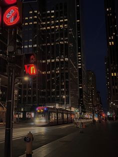 a city street at night with a train on the tracks and traffic lights in the foreground