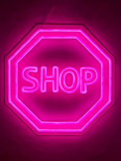 a neon sign with the word shop written on it in white letters, against a dark background