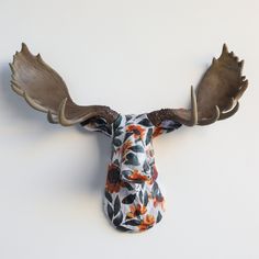 a deer's head with antlers and flowers on it is hanging from the wall