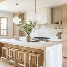 a kitchen island with four stools and a vase filled with flowers on the counter