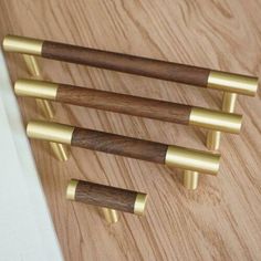 three brass and wood door handles on a wooden surface with white wall in the background