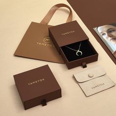 an open box with a necklace inside it next to a card and some other items