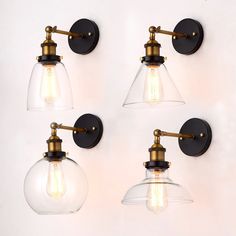 four clear glass lights are mounted on the wall with brass fittings and one light bulb is turned off