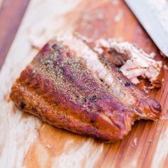 a piece of meat sitting on top of a wooden cutting board next to a knife