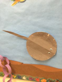 a paper plate with a bird on it next to a pink ribbon and some scissors