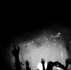 silhouettes of people raising their hands in front of a stage with lights and confetti