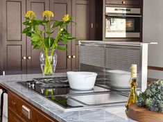 a vase with yellow flowers sitting on top of a kitchen counter next to a stove