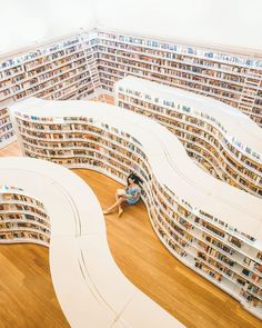 a woman sitting on the floor in a library filled with books