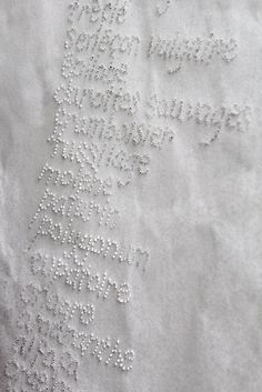 a close up of a piece of cloth with white thread on it and words written in small letters