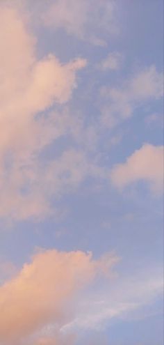 the airplane is flying high in the sky with clouds behind it and blue skies above