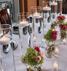 there are many vases with flowers and candles on the table