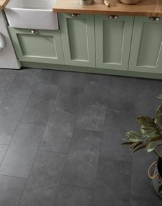 a kitchen with grey tile floors and green cabinets in the corner, along with a white sink