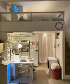 an apartment with a loft bed, desk and kitchenette in the middle of it