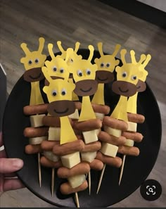 a black plate topped with lots of hot dogs covered in cheese and giraffe faces