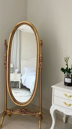 a mirror sitting on top of a table next to a white dresser and potted plant