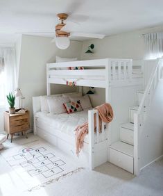 a white bunk bed sitting in a bedroom next to a stair case and rugs