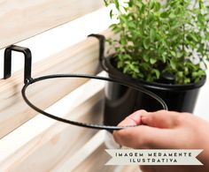 a person is holding the handle on a wooden bench next to a potted plant