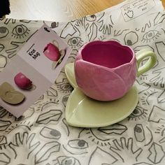 a pink cup and saucer sitting on top of a plate next to a box