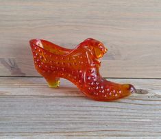 an orange glass bird sitting on top of a wooden table