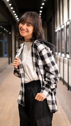 a woman in black and white checkered jacket posing for the camera with her hands on her hips