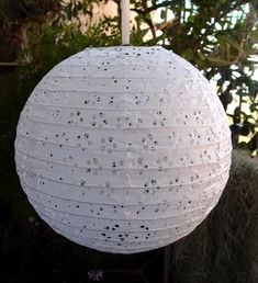 a white paper lantern hanging from a tree