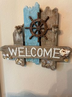 a wooden sign that says welcome with a ship wheel on the front and side of it