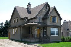 a large gray house sitting on top of a lush green field