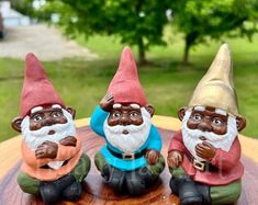 three gnome figurines sitting on top of a wooden table