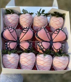 chocolate covered strawberries are in a box with pink frosting and green leaves on them