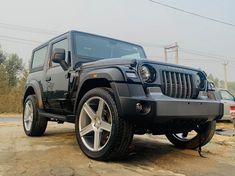 a black jeep parked on top of a dirt road