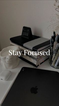 an apple computer sitting on top of a white desk next to a stack of books