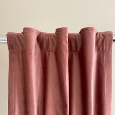 a pink curtain hanging on the side of a window