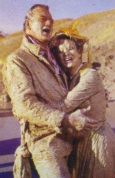 an old man and woman are hugging in the dirt with their faces covered by mud