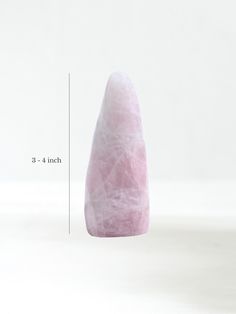 a large pink stone sitting on top of a white table next to a measuring ruler