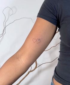 a woman's arm with a small heart tattoo on the left side of her arm