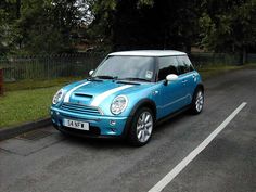 a small blue car is parked on the side of the road