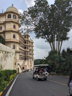 a group of people riding on the back of a golf cart down a curvy road