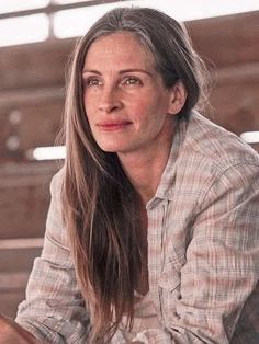 a woman with long hair is sitting on a bench and looking off into the distance