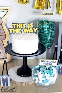 there is a cake on the table with decorations around it and balloons in the background