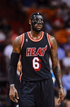 a basketball player wearing a black face mask on the court with fans in the background