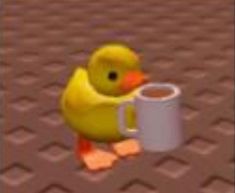 a yellow rubber duck holding a coffee mug in its beak and standing on the ground